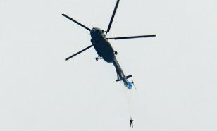 Parachute jumper hangs on helicopter tail during exercises